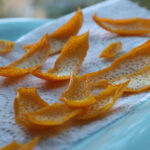 Curled dried orange peels on a blue cloth.