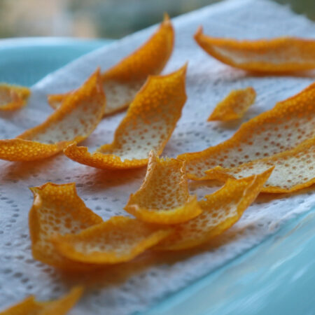Curled dried orange peels on a blue cloth.