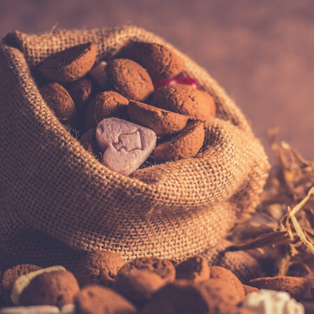 Burlap sack with spices to make the pfeffernusse spice blend on a dark background.